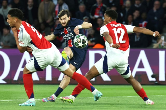 Le stratège géorgien du Paris SG Khvicha Kvaratskhelia (C) frappe entre deux défenseurs d'Arsenal, en demi-finale de la Ligue des champions, le 7 mai 2025 au Parc des Princes