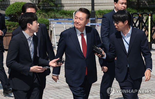 Former President Yoon Suk Yeol (C) looks at his supporters as he appears at the Seoul Central District Court in the capital on May 26, 2025, to attend the fifth hearing of a trial over insurrection charges in connection with his declaration of martial law. (Yonhap)