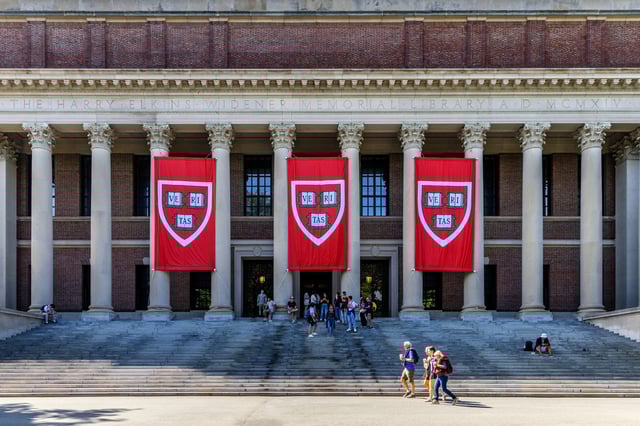 Cambridge, Massachusetts, USA - August 31, 2024: Crowd of people in front of the Harry Elkins Widener Memorial Library (c. 1915). Harvard VERITAS shield banners hang in front of building.