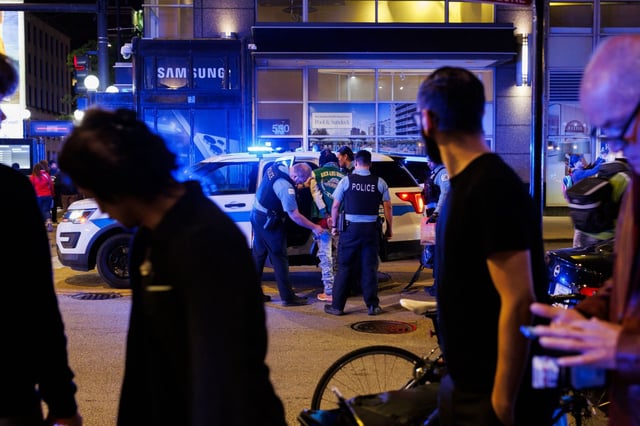 Police officers detain a person near a scene where a 22-year-old man was stabbed in the back in the 700 block of North State Street, May 25, 2025. (Armando L. Sanchez/Chicago Tribune)