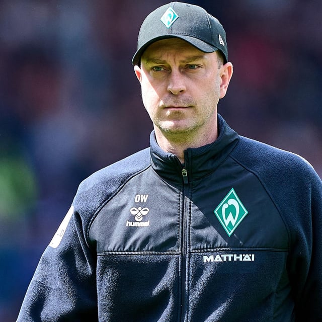 Werder-Trainer Ole Werner geht mit schwarzer Kappe auf dem Kopf konzentriert zu seiner Trainerbank vor einem Spiel.