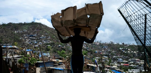 Un homme transporte des matériaux pour reconstruire sa maison à Mamoudzou, à Mayotte, le 2 janvier 2025