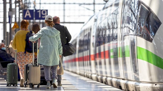 Reisende mit Gepäck laufen am Frankfurter Hauptbahnhof an einem Zug entlang.
