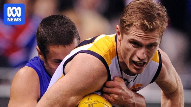 AFL player Adam Selwood tries to handball while being tackled. 