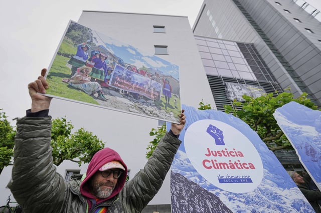 A protestor demands climate justice in front of the Higher Regional Court in Hamm, Germany, ahead of the verdict in the climate lawsuit brought by Peruvian farmer Luciano Lliuya against German energy company RWE, Wednesday, May 28, 2025. (AP Photo/Martin Meissner)