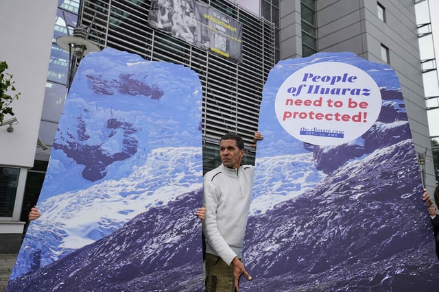 A protestor demands climate justice in front of the Higher Regional Court in Hamm, Germany, ahead of the verdict in the climate lawsuit brought by Peruvian farmer Luciano Lliuya against German energy company RWE, Wednesday, May 28, 2025. (AP Photo/Martin Meissner)