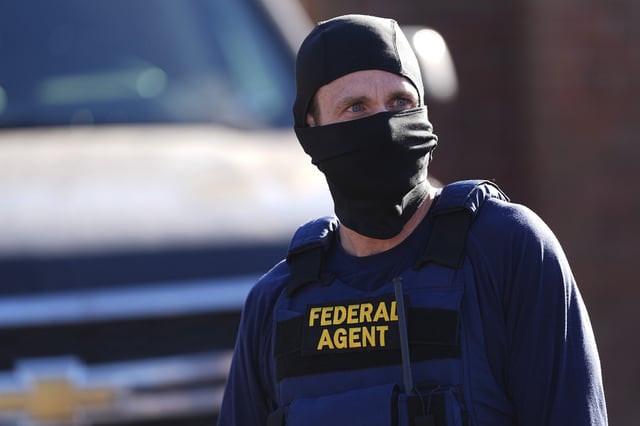 A federal agent stands watch outside an apartment complex during a raid Wednesday, Feb. 5, 2025, in east Denver.
