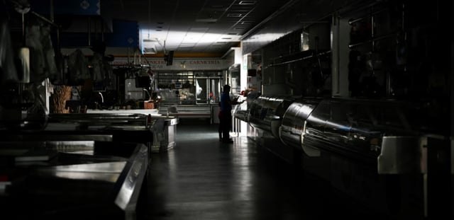 Un homme et un enfant dans un marché couvert plongé dans le noir lors de la panne électrique massive du 28 avril 2025, à Vigo, dans le nord-ouest de l'Espagne