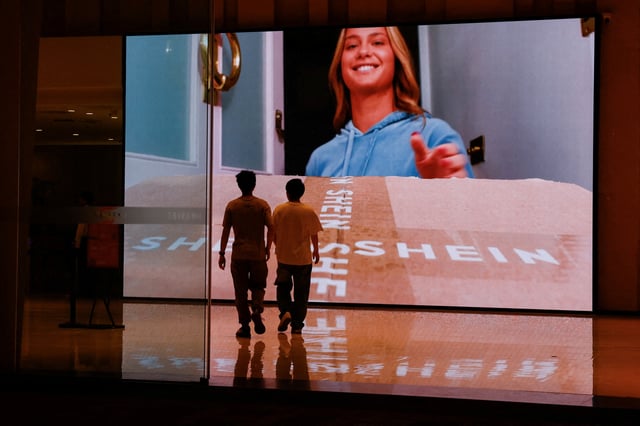 People walk past a screen showing a promotional video of Shein at the company's office building in Guangzhou, Guangdong province, China April 16, 2025. REUTERS/Tingshu Wang/File Photo