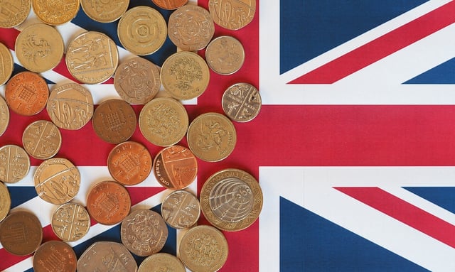 Pound coins GBP, currency of United Kingdom, over the Union Jack