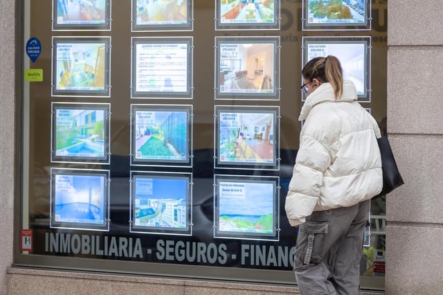 Una joven pasa delenta de un inmobiliaria de A Coruña.