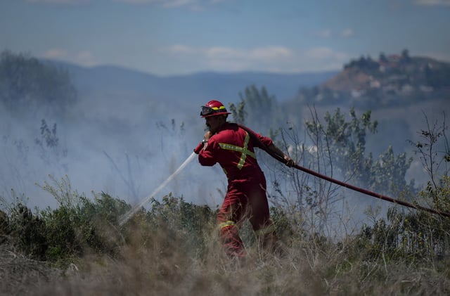 A firefighter directs water on a grass fire burning in Kamloops, B.C., June 5, 2023. THE CANADIAN PRESS/Darryl Dyck
