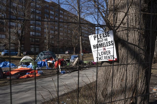 A sign advocating for support for the homeless is seen through a fenced-in homeless encampment in Victoria Park in Halifax's downtown on March 4, 2024. THE CANADIAN PRESS/Darren Calabrese