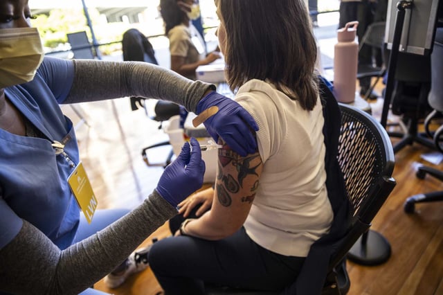 Christina Varna, right, receives a COVID-19 vaccine at the Kaiser Permanente adult vaccine clinic in San Francisco in September. The federal government recently announced new restrictions on COVID vaccine access.