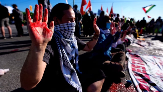 Protesters with fake blood on their hands sit on the road outside the Canadian Association of Defence and Security Industries annual defence industry trade show in Ottawa on Wednesday.