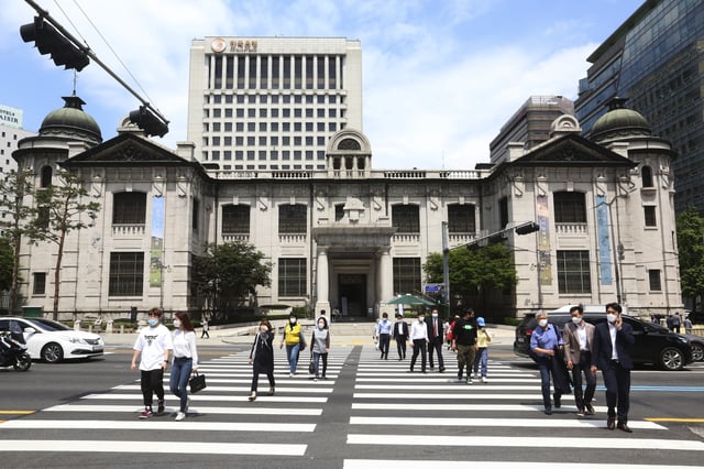 FILE - People wearing face masks walk by the headquarters of the Bank of Korea in Seoul, South Korea, Thursday, May 28, 2020. (AP Photo/Ahn Young-joon, File)