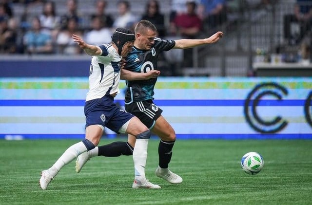  Vancouver Whitecaps’ Bjorn Inge Utvik, front left, defends against Minnesota United’s Robin Lod during the first half of an MLS soccer match, in Vancouver.