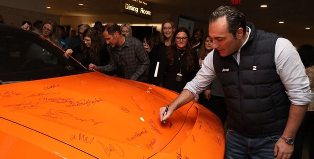 Filosa firmando en un vehículo de Stellantis durante un acto.