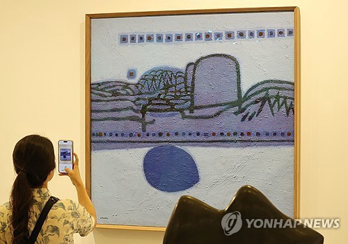 A visitor takes a photo of Kim Whan-ki's painting on display at Frieze Seoul at the Convention and Exhibition Center (COEX) in southern Seoul, in this file photo taken Sept. 4, 2024. (Yonhap) 