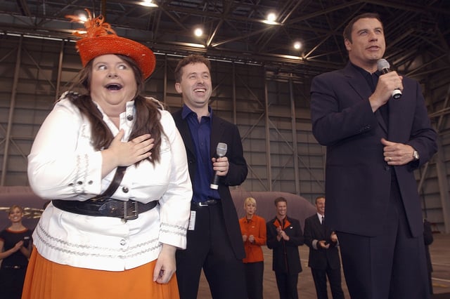 Australian actor Magda Szubanski, left, mocks her desire for American movie star John Travolta, right, during the unveiling of airline Jet Star's first plane in Sydney, May 10, 2004. (AP Photo/Rick Rycroft, File)