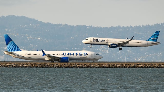 A United Airlines plane prepares for takeoff as a JetBlue plane lands at San Francisco International Airport in 2023.