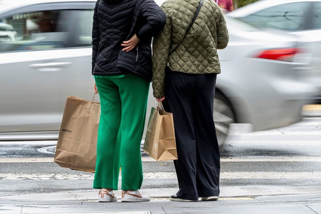 Shoppers hold bags while waiting to cross Post Street in San Francisco on March 27.