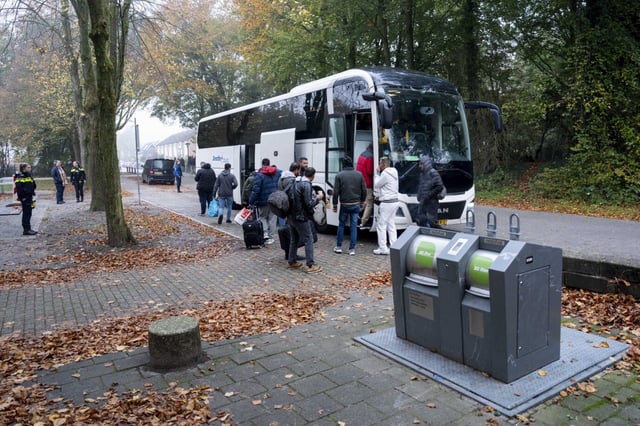 Auf einem Parkplatz steht ein großer Reisebus, daraus steigen migrantisch aussehende Männer - Symbolbild für die vielen Asylverfahren, die derzeit Sachsen belasten