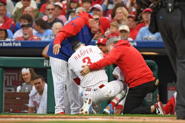 May 27, 2025; Philadelphia, Pennsylvania, USA; Philadelphia Phillies first base Bryce Harper (3) is looked at by Philadelphia Phillies manager Rob Thomson (59) and  trainer Joe Rauch after being hit by a pitch during the first inning against the Atlanta Braves at Citizens Bank Park. Mandatory Credit: Eric Hartline-Imagn Images
