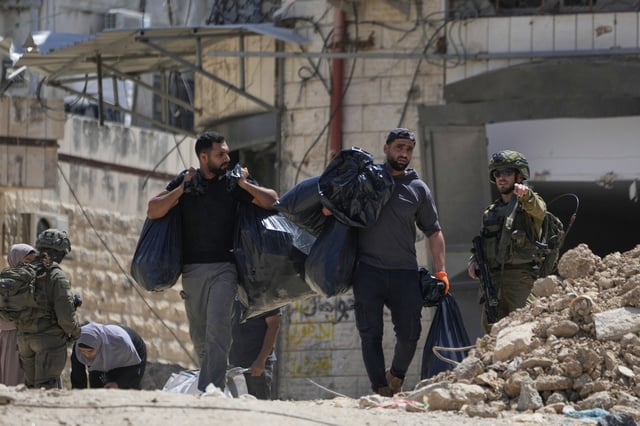 Israeli soldiers check the identification cards of residents of the now evacuated Palestinian refugee camp of Tulkarem who return to collect belongings before the destruction of their homes as Israeli forces prepared to carry out the demolition of homes across the two refugee camps of the Israeli occupied West Bank city of Tulkarem, Thursday, May 29, 2025. (AP Photo/Nasser Nasser)