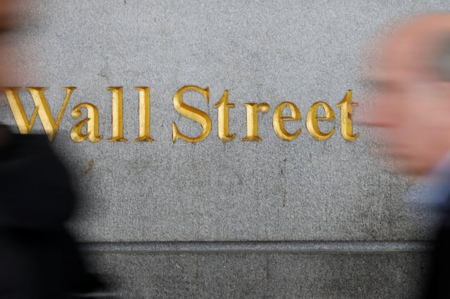 People walk by a Wall Street sign close to the New York Stock Exchange (NYSE) in New York, U.S., April 2, 2018. REUTERS/Shannon Stapleton/File Photo