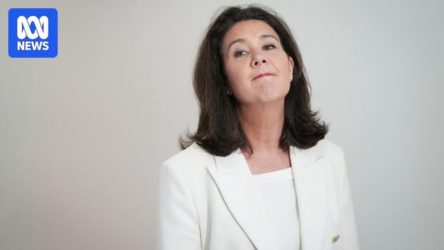 Hume, wearing a white blazer and shirt against a white background.