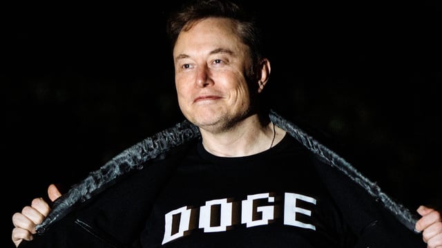 Elon Musk shows off a shirt that says "DOGE" as he walks on the South Lawn of the white House after stepping off Marine One upon arrival to the White House in Washington, DC on March 9, 2025.