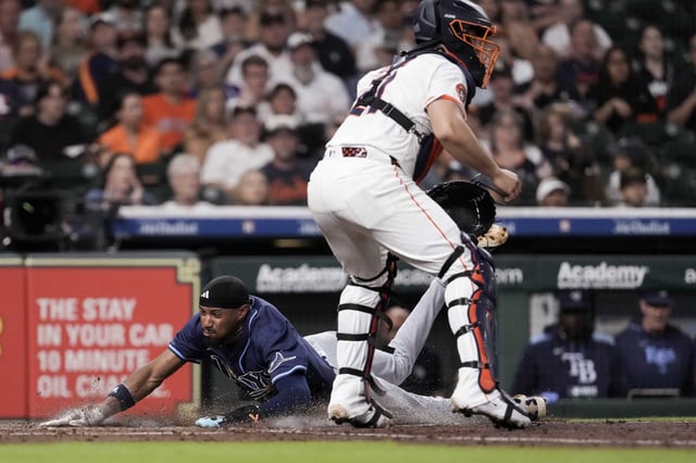 Tampa Bay Rays Chandler Simpson (14) scores on a throwing error by Houston Astros catcher Yainer Diaz as Simpson stole third during the fourth inning of an MLB baseball game in Houston, Thursday, May 29, 2025.