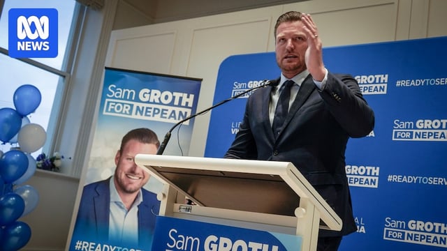 Man with hand raised with political advertising behind him