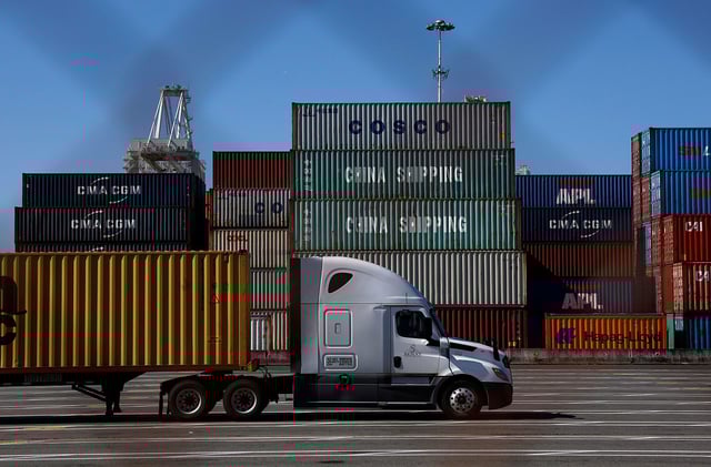 A truck drives by stacked shipping containers at the Port of Oakland on May 20 in Oakland, California. The Port of Oakland saw a 14.7% decrease in overall cargo volume in April after the Trump administration's tariffs were enacted.