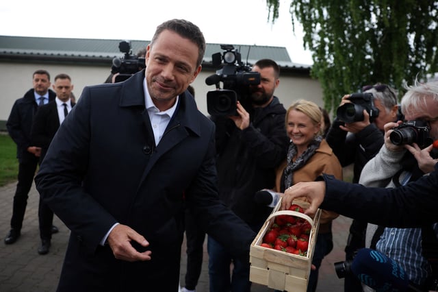 Warsaw Mayor Rafal Trzaskowski, Civic Coalition presidential candidate, offers strawberries to media representatives during a visit to the Weglewski farm, ahead of the second round of Polish presidential election, in Buczek, May 29, 2025. REUTERS/Kacper Pempel