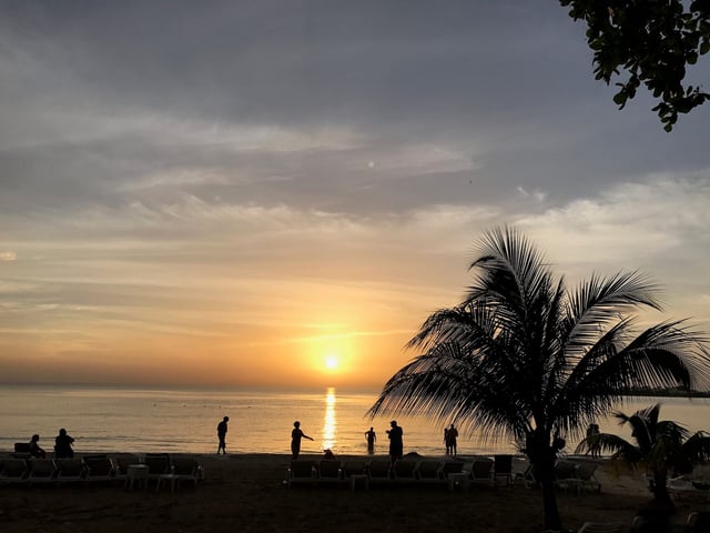 People are silhouetted on the beach during sunset in Negril, Jamacia on May 21, 2017.