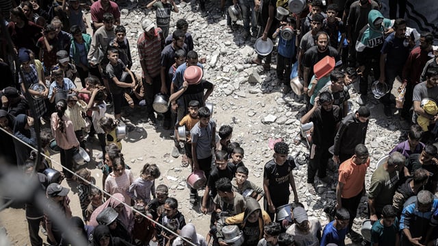 Displaced Palestinians line up in long queues to receive food distributed by aid organizations at Sheikh Radwan neighborhood in Gaza City, Gaza on Tuesday.