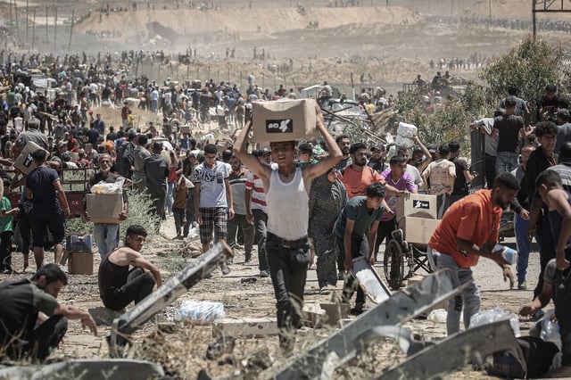 Palestinians carry boxes of humanitarian aid collected from a distribution center in the Netzarim Corridor, central Gaza Strip, on Thursday.