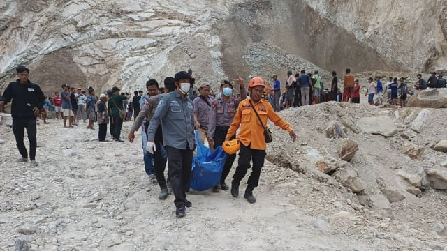 BNPB operatives carrying a victim after a rock collapse in indonesia