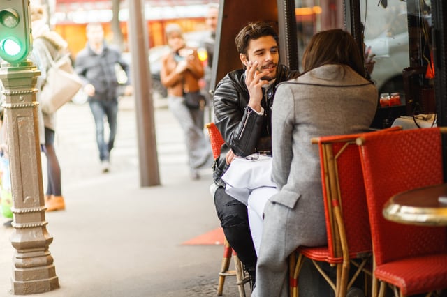 A man is seen smoking on a café terrace. 