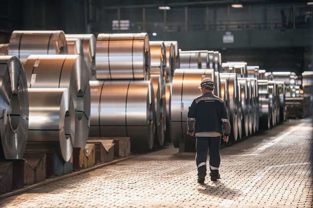 A worker walks past coils of finished steel at the Thyssenkrupp steel mill on March 20 in Duisburg, Germany.