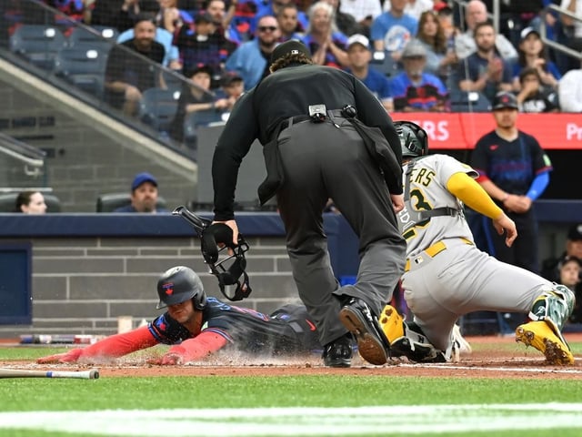 Blue Jays infielder Ernie Clement (22) slides safely into home ahead of a tag by Athletics catcher Shea Langeliers (23) in the second inning of a Major League Baseball game in Toronto on Friday, May 30, 2025.