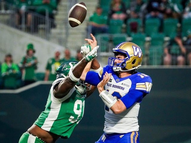 Saskatchewan Roughriders defensive lineman Aaron Patrick (91) blocks Winnipeg Blue Bombers quarterback Chase Artopoeus' (16) pass attempt during the first half of pre-season CFL football action in Regina, on Friday, May 30, 2025.