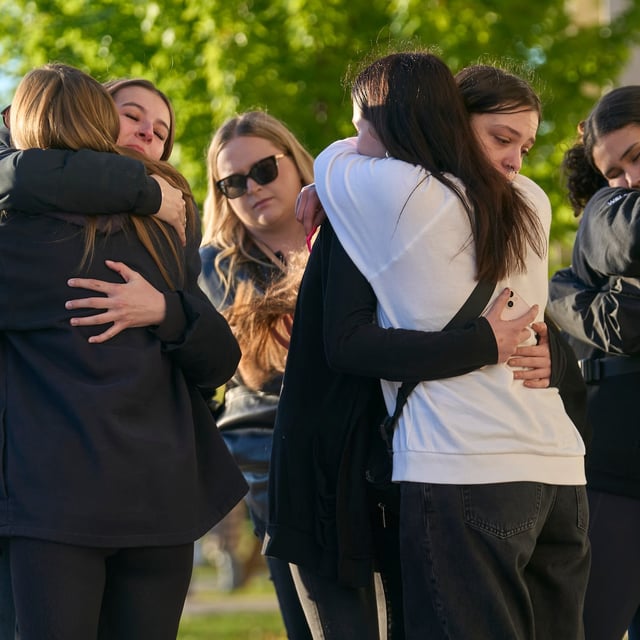 Young people hug near a memorial at Walkerton District Community School in Walkerton, Ont. on Sunday. Four students and a teacher from the school were killed in a vehicle accident on the way back from a softball tournament in Dorchester, Ont.