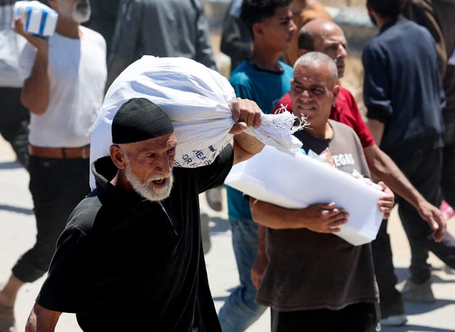 Palestinians carry aid supplies which they received from the U.S.-backed Gaza Humanitarian Foundation, in the central Gaza Strip, May 29, 2025. REUTERS/Ramadan Abed REFILE - CORRECTING LOCATION FROM "NEAR AN AREA OF GAZA KNOWN AS THE NETZARIM CORRIDOR" TO "IN THE CENTRAL GAZA STRIP".