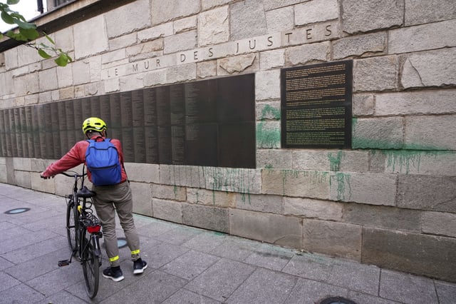 A cyclist looks at Paris' Shoah Memorial defaced with green paint after several Jewish sites across the capital were defaced with green paint. Saturday, May 31, 2025 in Paris. (AP Photo/Aurelien Morissard)