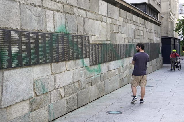 A man looks at Paris' Shoah Memorial defaced with green paint after several Jewish sites across the capital were defaced with green paint. Saturday, May 31, 2025 in Paris. (AP Photo/Aurelien Morissard)