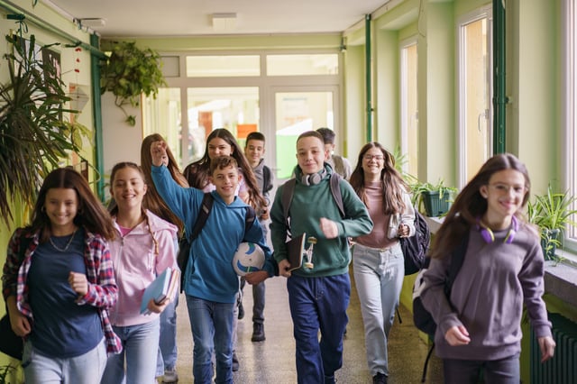 A group of happy teenagers run during the last day of school
