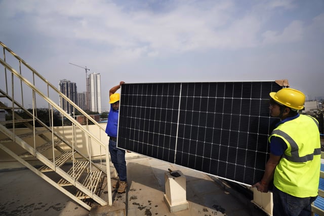 FILE - Workers of Solar Square carry a panel on the rooftop of a residence in Gurugram on the outskirts of New Delhi, India, Feb. 20, 2024. (AP Photo/Manish Swarup, File)